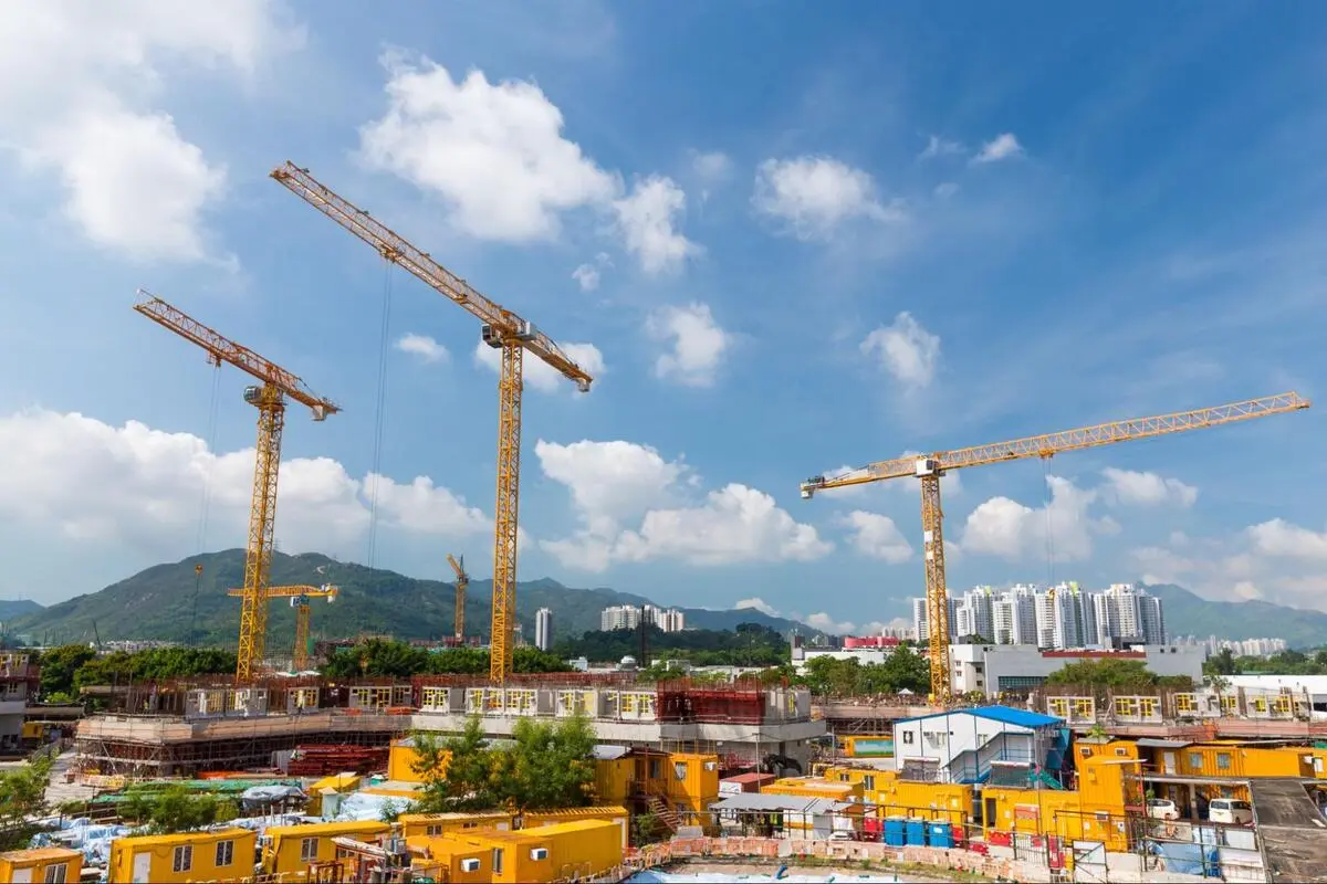 Active Urban Construction Site with Tower Cranes Yellow tower cranes at an active construction site.
