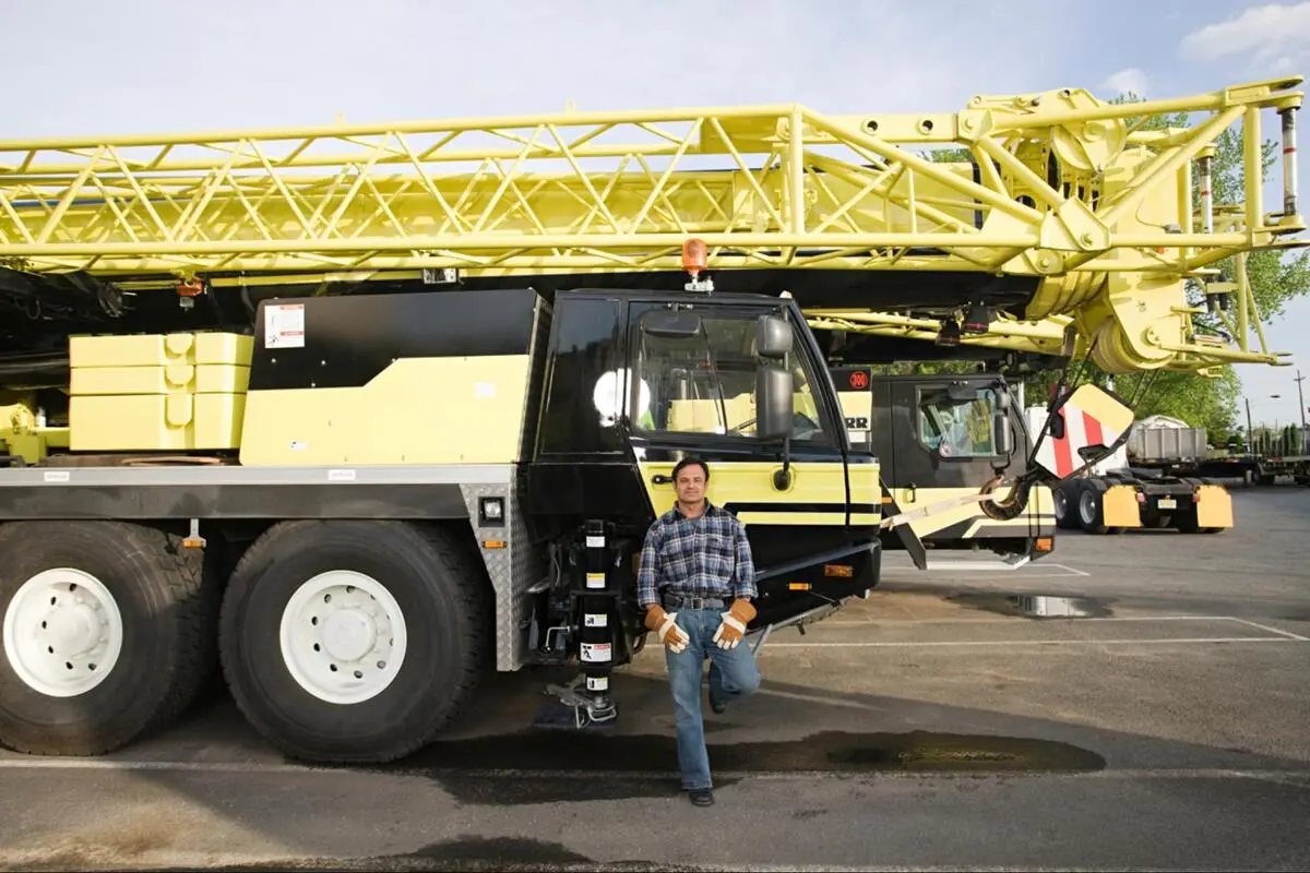 Heavy Equipment Maintenance Crane Parts Lead Time Male worker standing in front of a large yellow crawler crane in an outdoor equipment yard, representing heavy machinery maintenance and part lead time planning