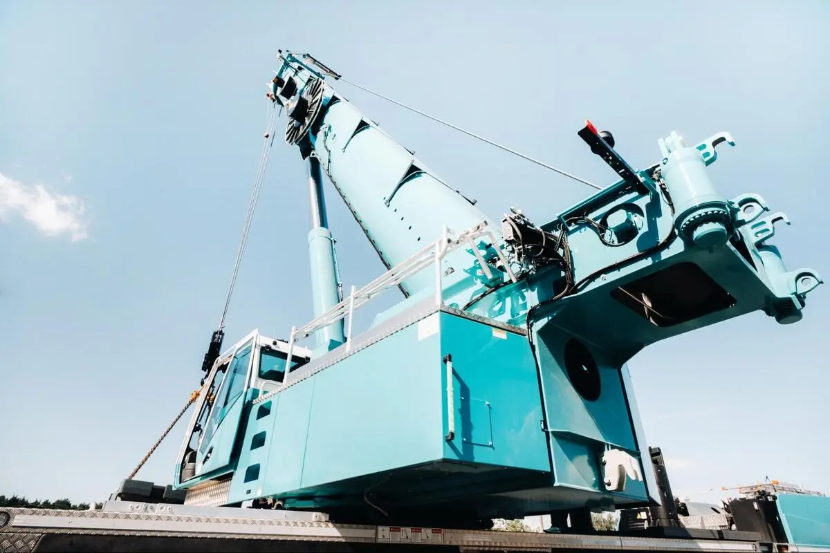 Close-up of a teal crawler crane's boom and hydraulic components